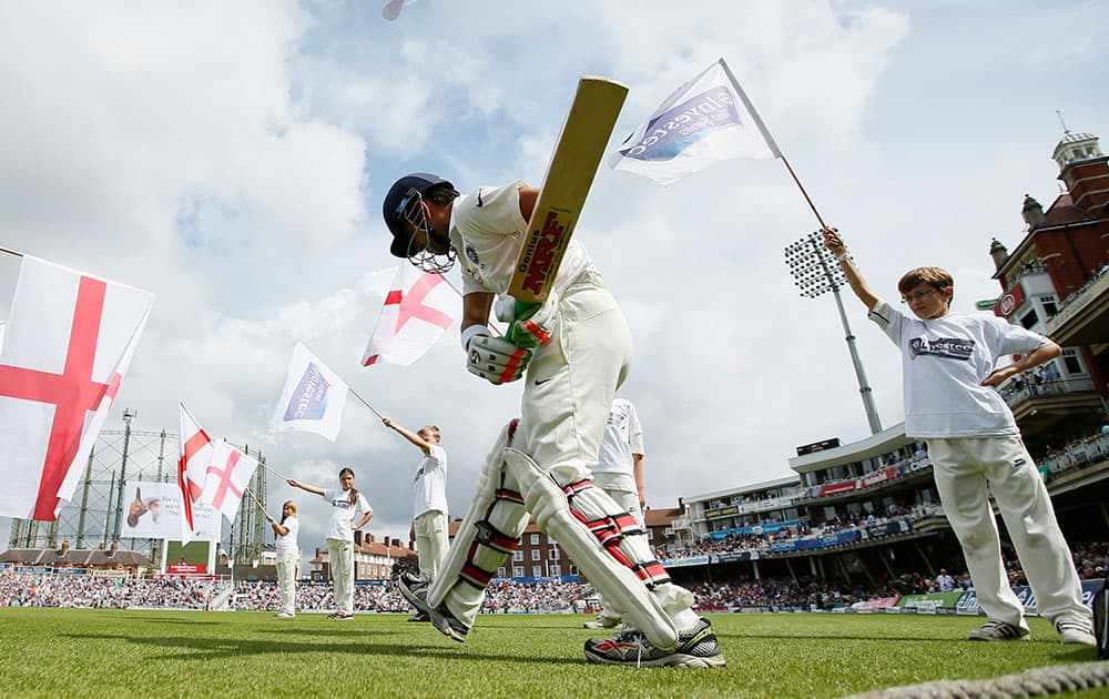 Gautam Gambhir walks onto the pitch past children waving flags at the start of the first day of the fifth test cricket match at Oval cricket ground in London.