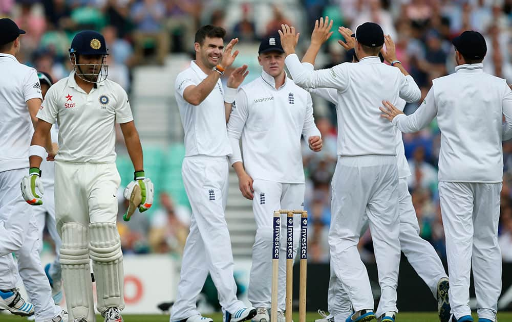 England's James Anderson, centre, celebrates with team mates after the wicket of India's Gautam Gambhir, left who walks off the pitch during the first day of the fifth test cricket match at Oval cricket ground in London.