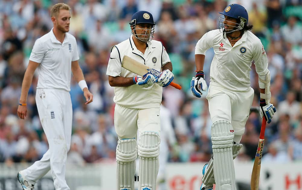 India's MS Dhoni, centre, and teammate Ishant Sharma run off the pitch after the end of their first inning with Dhoni falling to England's Stuart Broad during the first day of the fifth Test cricket match at Oval cricket ground in London.