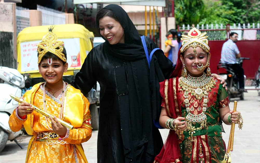 A muslim woman on the streets of Varanasi with her kids dressed as Lord Krishna and Radha returning home after a competition in school ahead of Janmashtami, in Varanasi.