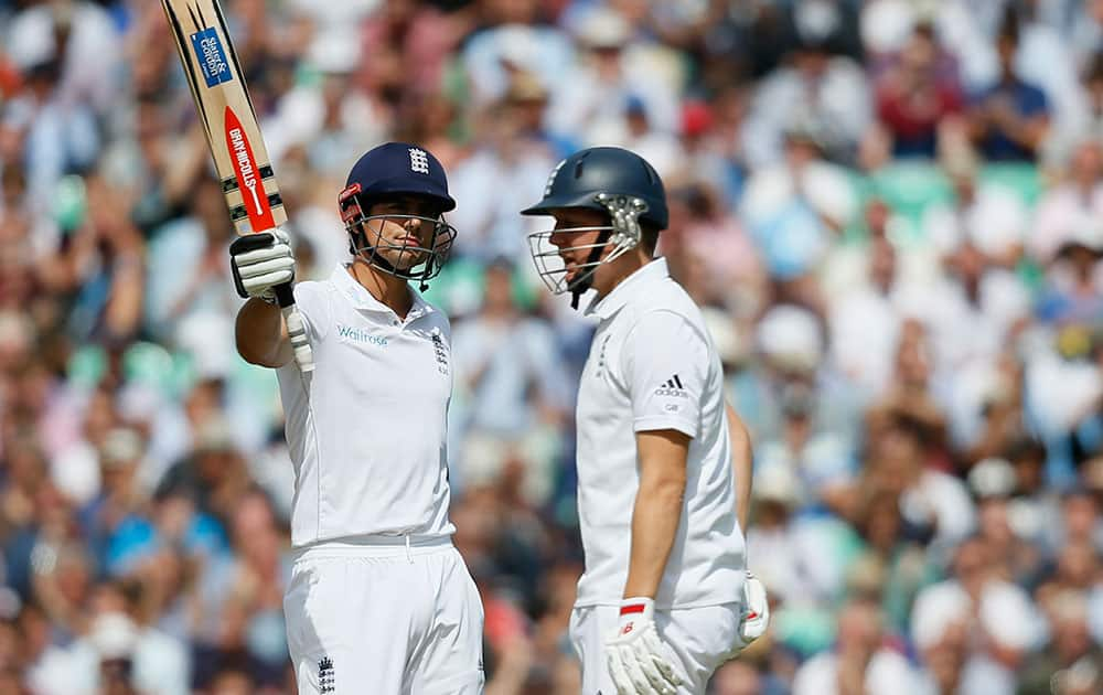 England's Alastair Cook, left raises his bat to acknowledge the crowd after scoring 50 runs not out against India during the second day of the fifth Test cricket match at Oval cricket ground in London.