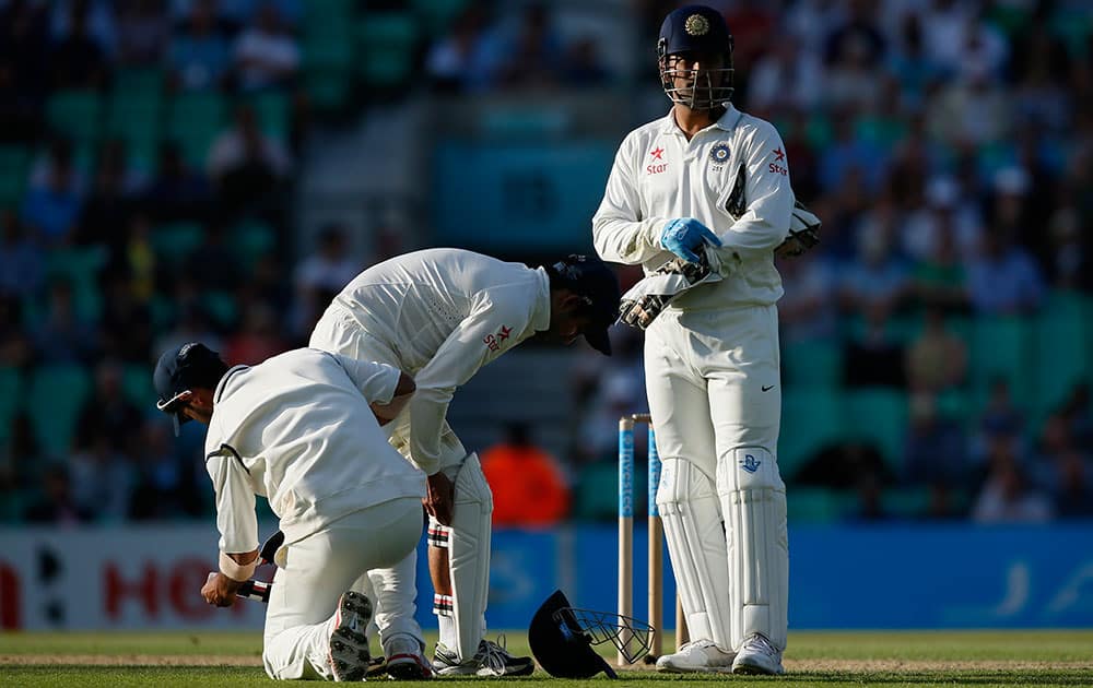 India's captain MS Dhoni, right, waits as his player pad up for close fielding during the second day of the fifth Test cricket match against England at Oval cricket ground in London.