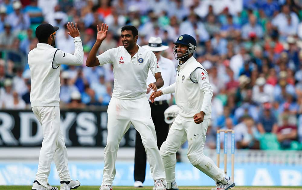 India's bowler Ravichandran Ashwin, centre, celebrates after taking the wicket of England's Gary Ballance caught by Cheteshwar Pujara, right, during the second day of the fifth test cricket match at Oval cricket ground in London.