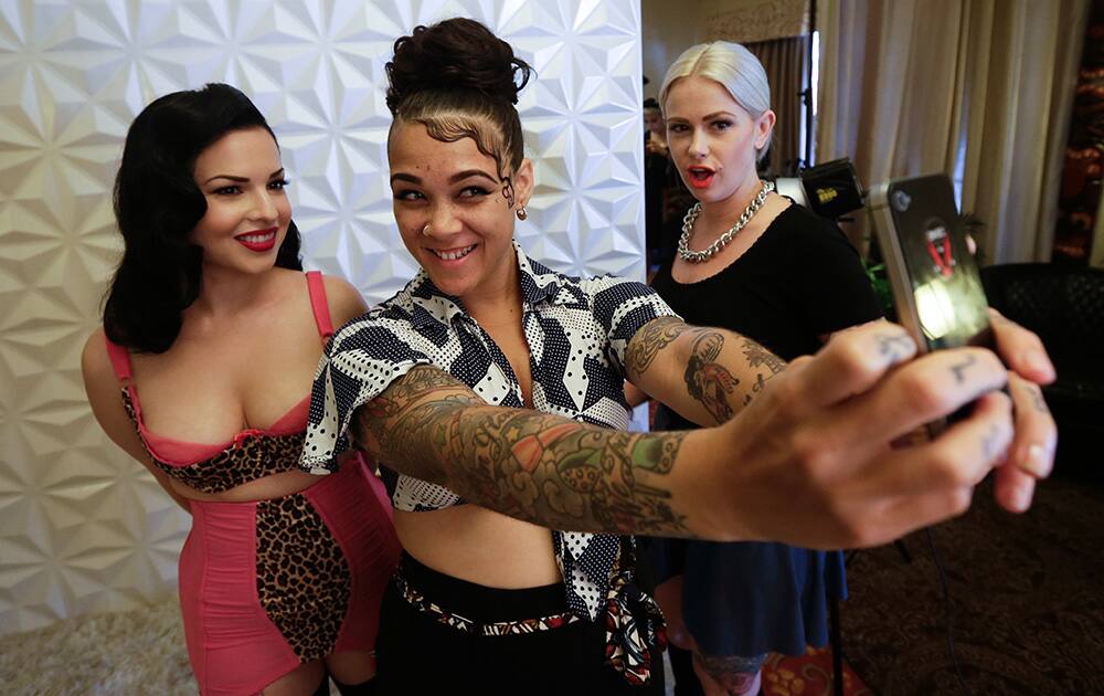 Stylist Madison Jane, center, takes a picture with Olivia Felix, left, as Melyssa Maria, right, looks on after a photo session during Tiki Oasis event, in San Diego.