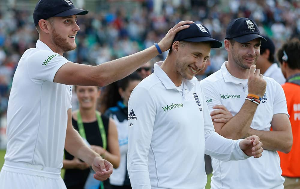 England's Stuart Broad, left, pats the head of his teammate Joe Root, center, as James Anderson looks on, after they defeated India in the final of the five test series to win 3-1, at Oval cricket ground in London.