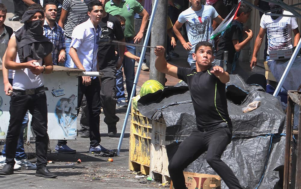 Palestinian protesters hurl stones at Israeli soldiers during clashes, following a protest against the Israeli military action over Hamas in Gaza, in the West Bank city of Hebron.