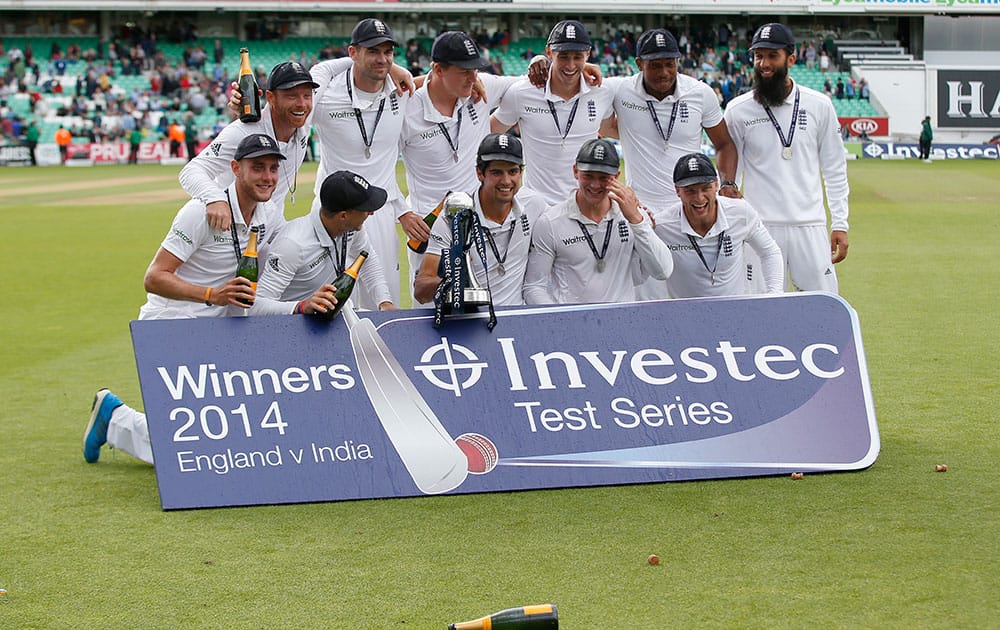 England cricket team Captain Alastair Cook holds the trophy as the team celebrate with champagne their 3-1 series win, after defeating India on the third day of the fifth test cricket match at Oval cricket ground in London.