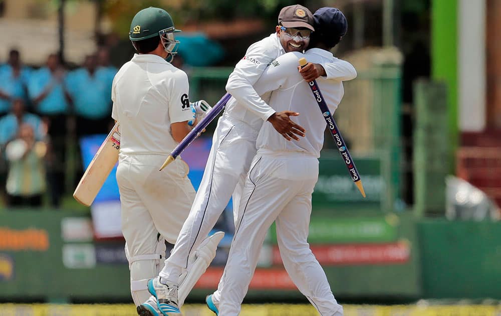 Sri Lanka's captain Angelo Mathews, right, lifts teammate Mahela Jayawardene as Pakistan's Saeed Ajmal walks off the field after Sri Lanka defeated Pakistan by 105 runs in their second test cricket match in Colombo, Sri Lanka.