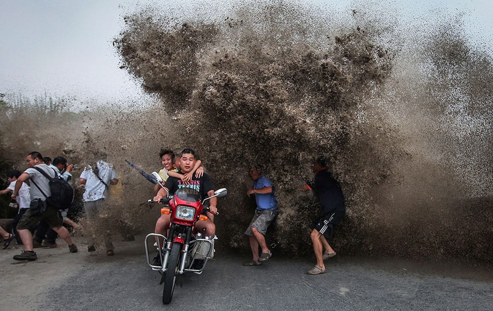 Bikers and spectators gathered to watch the Qiantang tidal bore run as a wave crashes inland on the banks of the Qiantang River in Hangzhou in east China`s Zhejiang province.