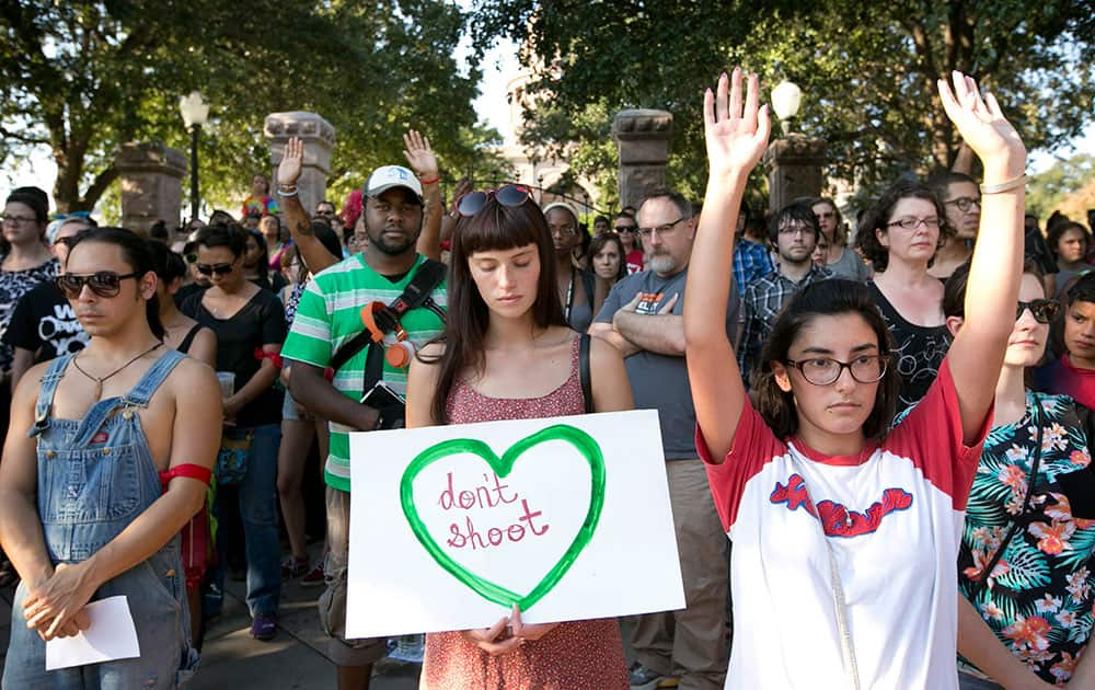 Julie Wier, middle, and Alicia Ramirez, right, observe a moment of silence during a vigil for victims of police brutality at the Capitol in Austin, Texas.
