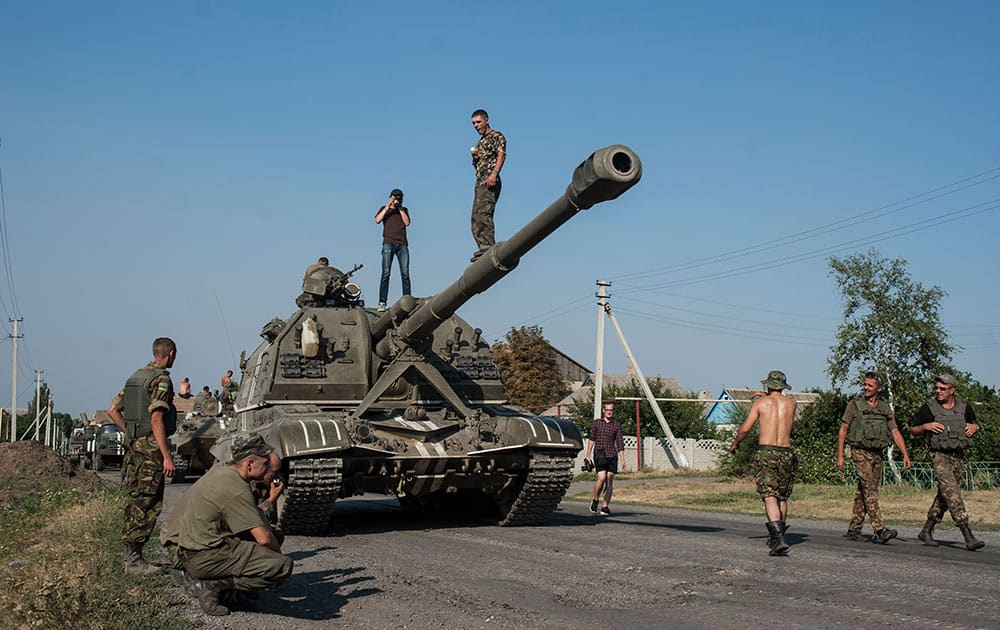 Ukrainian soldiers rest in their self-propelled guns as an army column of military vehicles prepares to roll to a frontline near Illovaisk, Donetsk region, eastern Ukraine.