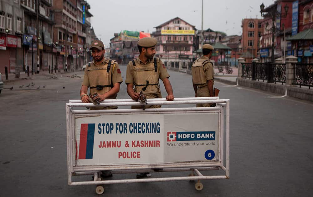 Policemen stand guard at a temporary check point during curfew in Srinagar.