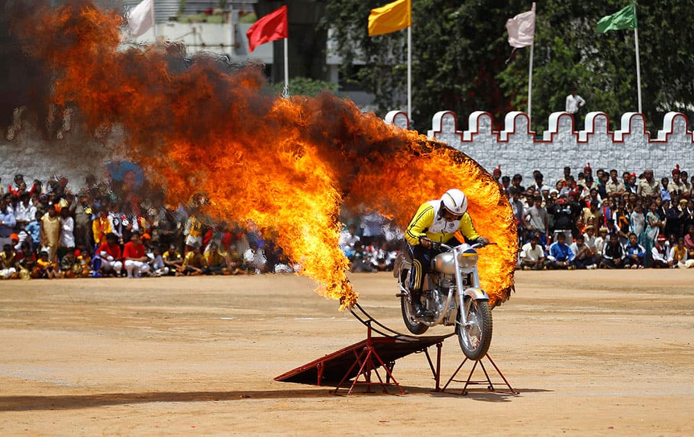 AN INDIAN ARMY OFFICER DRIVES THROUGH A BURNING RING AS HE PERFORMS A DAREDEVIL STUNT DURING INDEPENDENCE DAY CELEBRATIONS IN BANGALORE.