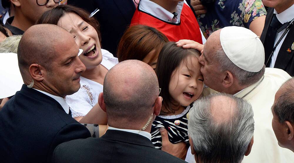 Pope Francis, kisses a child upon his arrival for the mass of the Assumption of Mary at Daejeon World Cup stadium in Daejeon, south of Seoul, South Korea.