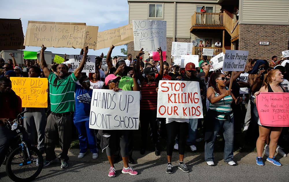 Demonstrators peacefully gather, at the site where Michael Brown was shot and killed by police in Ferguson, Mo.