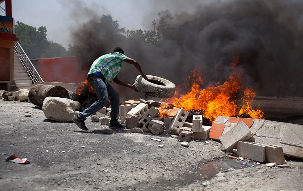 Supporter of Haiti`s former President Jean-Bertrand Aristide burns tires at a barricade on the street during a protest to support him in Port-au-Prince, Haiti.