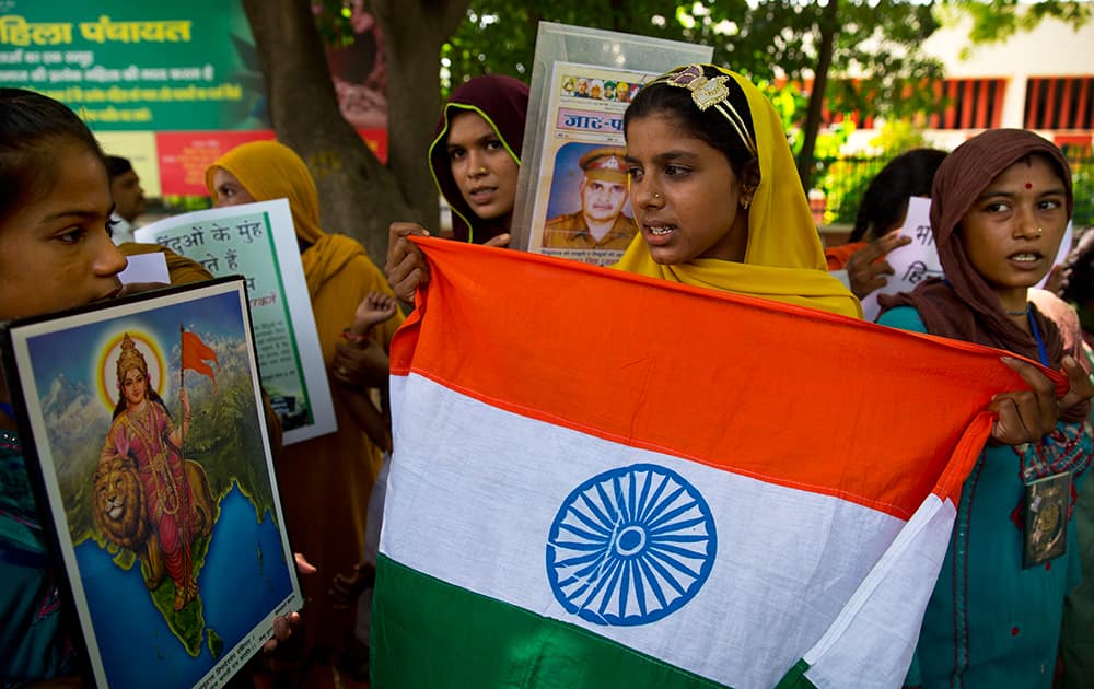 Hindu refugees from Pakistan who live in India hold the Indian flag and a picture of Mother India, left, as they gather for a protest on Pakistan’s Independence Day in New Delhi.