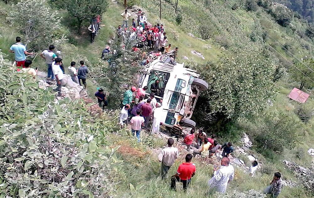 People near a passenger bus that rolled into a deep gorge in Sanwal, Chamba.