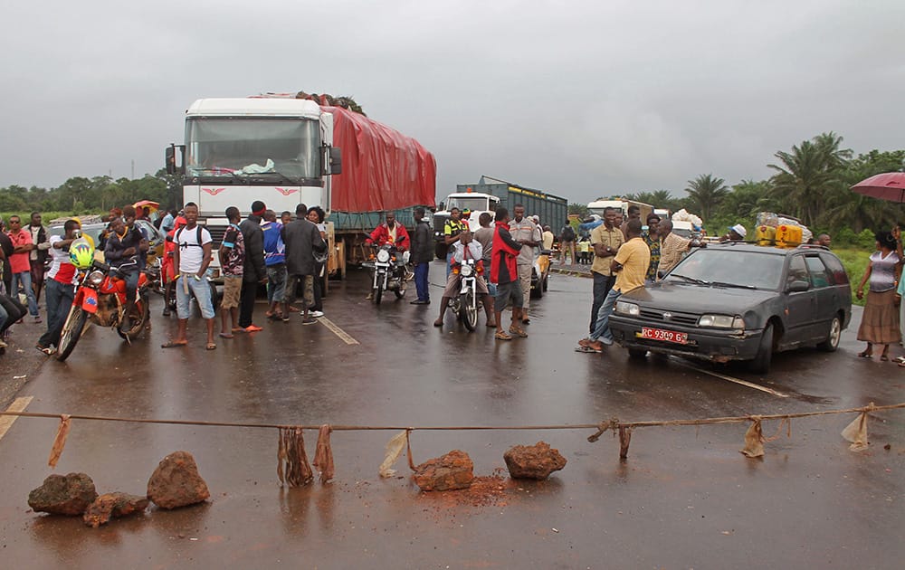 Stranded people stand behind a rope across the road that separates Guinea and Sierra Leone, and works as a makeshift border control checkpoint at Gbalamuya-Pamelap, Guinea. As Guinea closed its border with Sierra Leone at the weekend in an attempt to halt the spread of the deadly Ebola virus, people and goods were not able to cross to either side. 