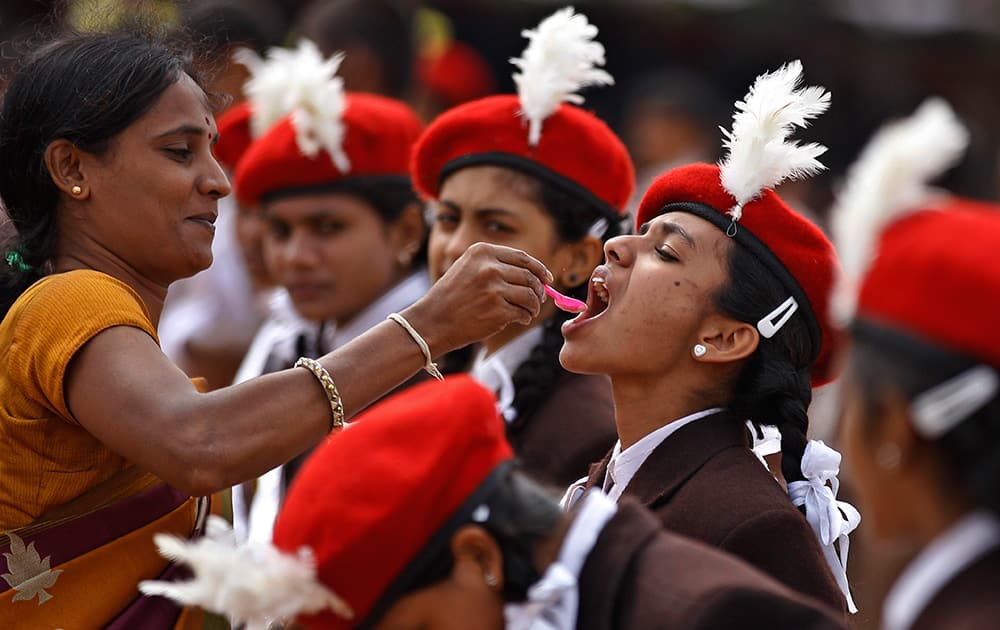 A school teacher feeds glucose powder to a student to give her energy during a rehearsal for the Independence Day celebrations in Bangalore.