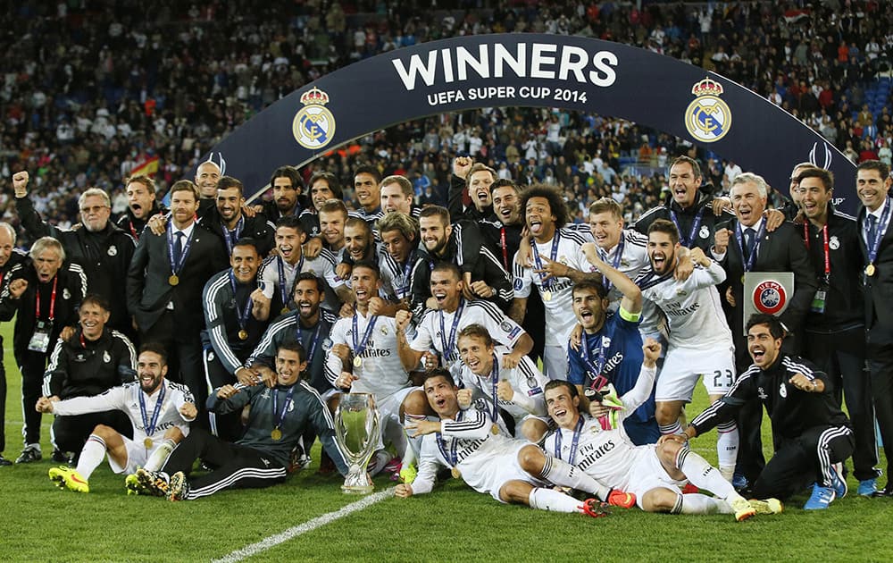 Real Madrid players pose with the trophy after winning the UEFA Super Cup soccer match between Real Madrid and Sevilla in Cardiff City Stadium, in Cardiff, Wales.