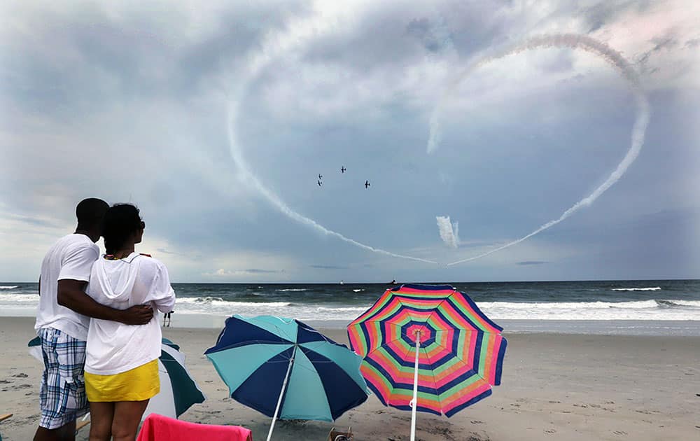 Phil Terry and Linda Laosongkram, both of Galloway Township, N.J., watch the Geico Skytypers perform a practice run in preparation for the Thunder Over the Boardwalk air show from the beach.