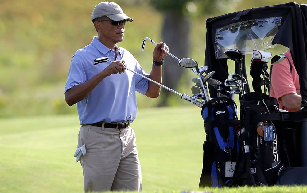 President Barack Obama returns clubs to the cart while golfing at Vineyard Golf Club, in Edgartown, Mass., on the island of Martha`s Vineyard. 