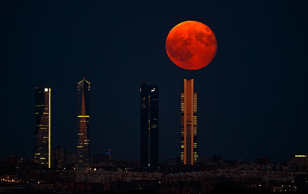 The moon rises in the sky as seen through the Four Towers or C.T.B.A. (Cuatro Torres Business Area), one of the main symbols of Madrid.