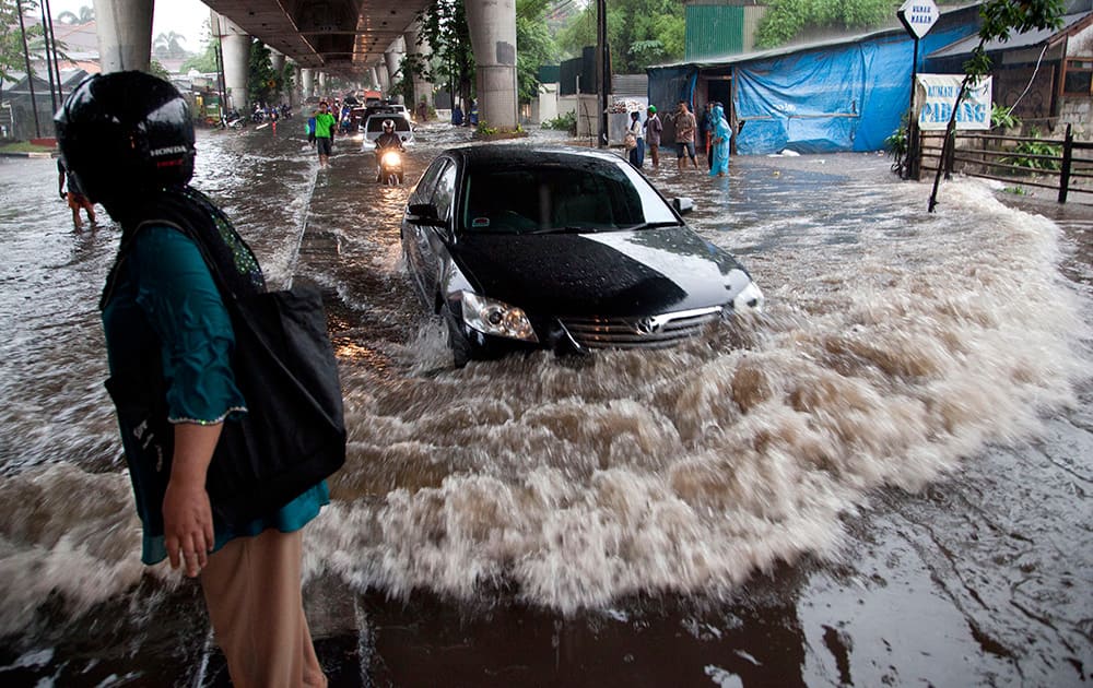 A car drives through a flooded road in Jakarta, Indonesia. The unseasonal rains flooded many areas of South Jakarta in the late afternoon causing much traffic congestion as commuters attempted to make their way home. 