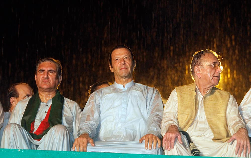 Pakistan`s cricketer-turned-politician Imran Khan, center, with other his party leaders attend an anti government rally during heavy rain in Islamabad.