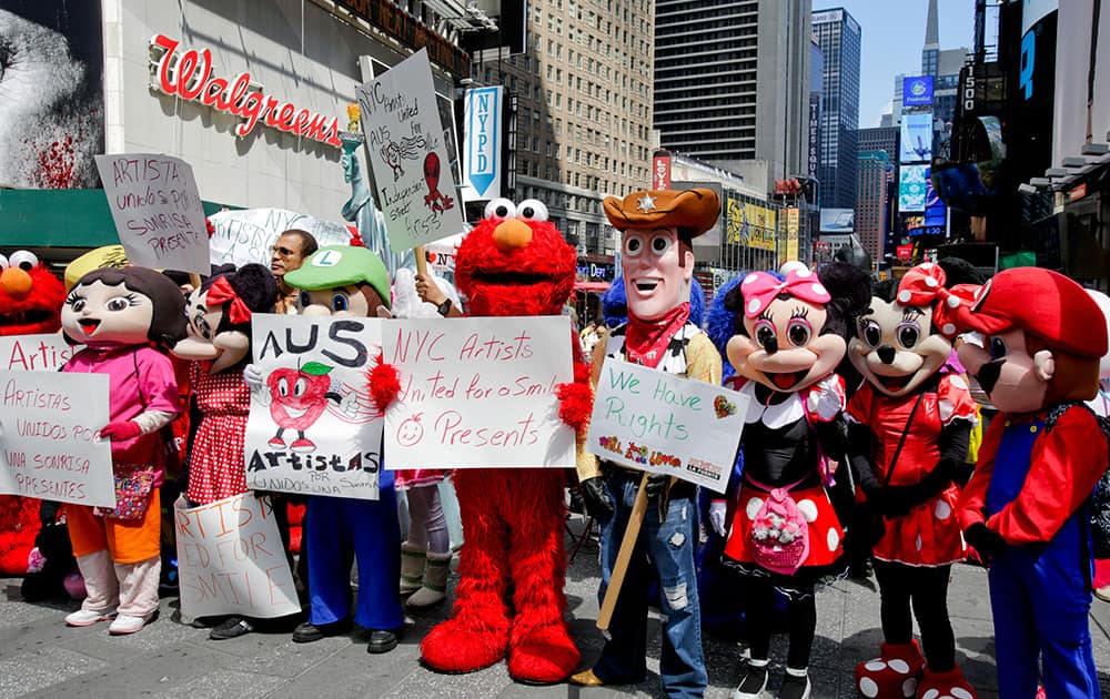 Costumed characters hold signs prior to a press conference held by NYC Artists United for a Smile at Times Square in New York.