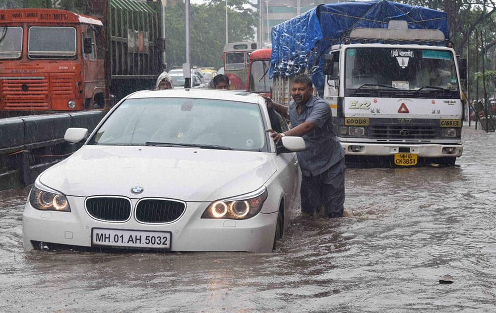 Vehicles move slowly at a waterlogged road after heavy rains in Mumbai.