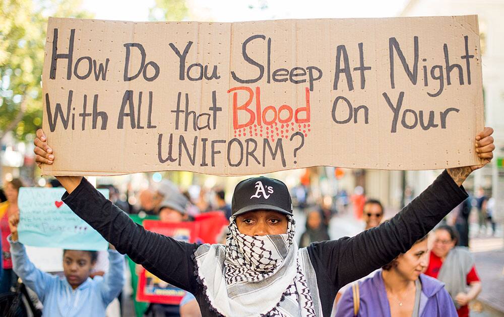 A woman, who declined to give her name, joins several hundred others in Oakland, Calif., during a protest against the shooting of Michael Brown, an unarmed black 18-year old by a white police officer in Ferguson, Mo. 