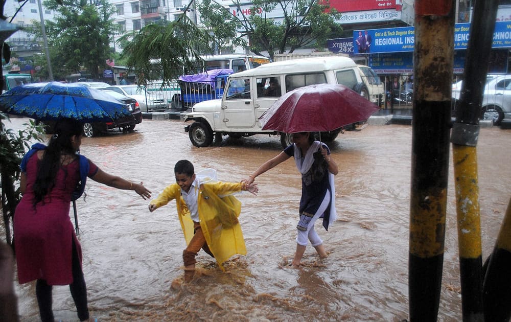 Parents with their children wade through a waterlogged GS Road after heavy showers in Guwahati.