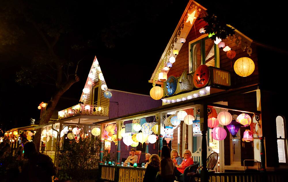 People walk past cottage homes decorated with lanterns during the `Grand Illumination Night,` an annual tradition since 1868 when multitudes of paper lanterns are lit for one night in a historic neighborhood known as the `Camp Ground,` in Oak Bluffs, Mass., on the island of Martha`s Vineyard. 