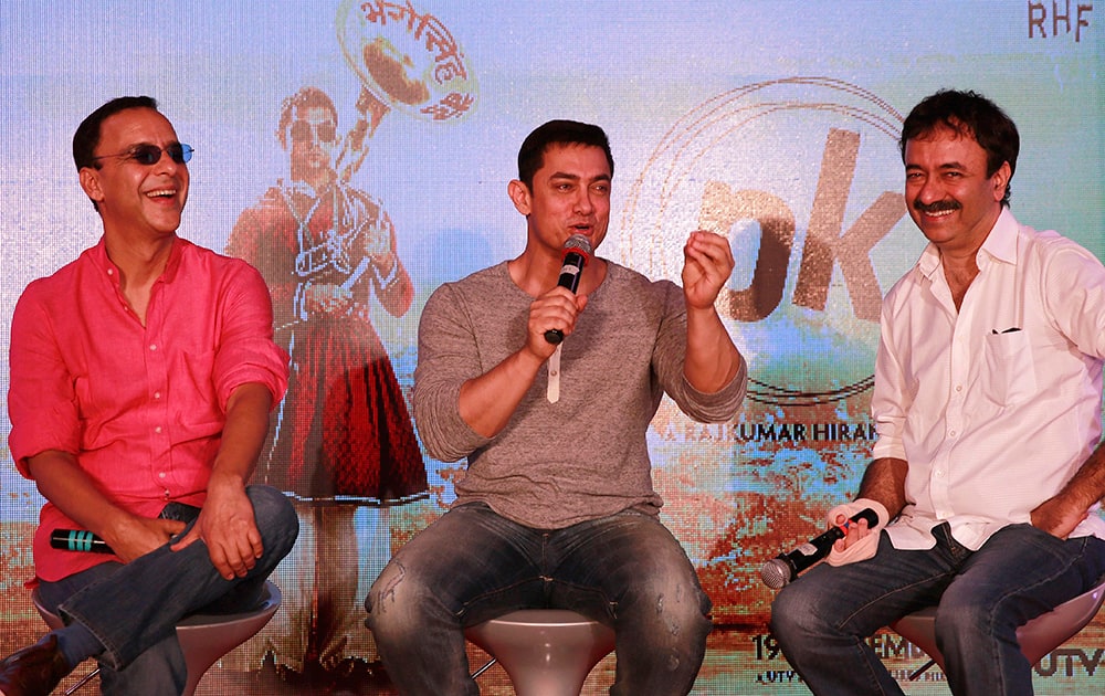 Director Rajkumar Hirani right, and producer Vidhu Vinod Chopra, left, enjoy a lighter moment as Bollywood actor Aamir Khan speaks during the unveiling of the second poster of his upcoming film PK in Mumbai.