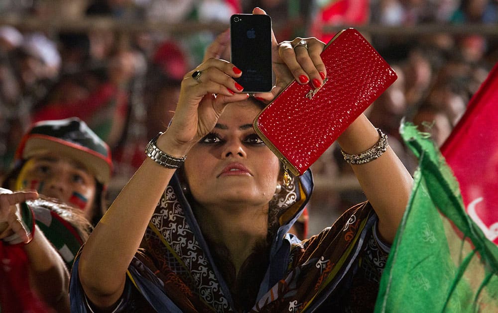 A supporter of Pakistan`s cricketer-turned-politician Imran Khan uses her cell phone to take picture of Khan during a protest near the parliament building in Islamabad, Pakistan.