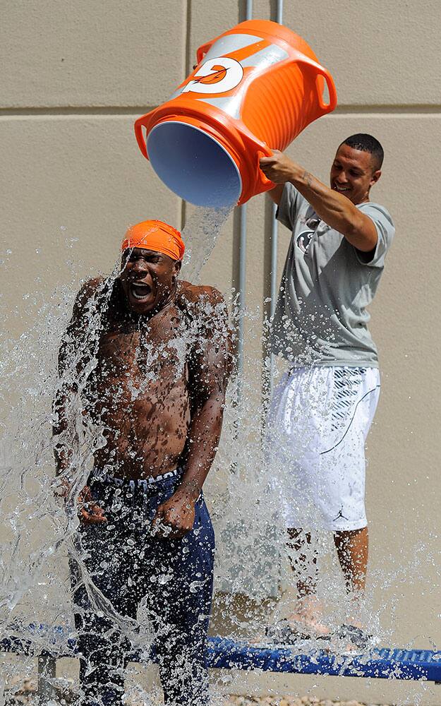 Denver Broncos` Tony Carter, right, pours water on Duke Ihenacho, left, for the ALS ice bucket challenge after an NFL football practice in Englewood, Colo.