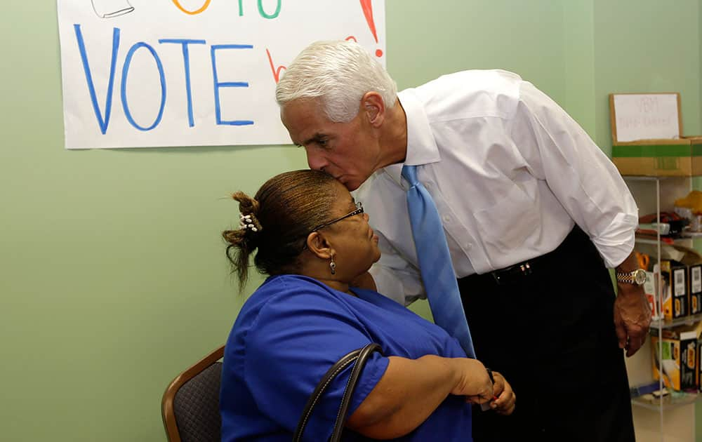 Former Florida Gov. Charlie Crist, right, kisses volunteer Edouine Belot, of Fort Lauderdale, left, on the head during a visit to a phone bank, in Fort Lauderdale, Fla. 