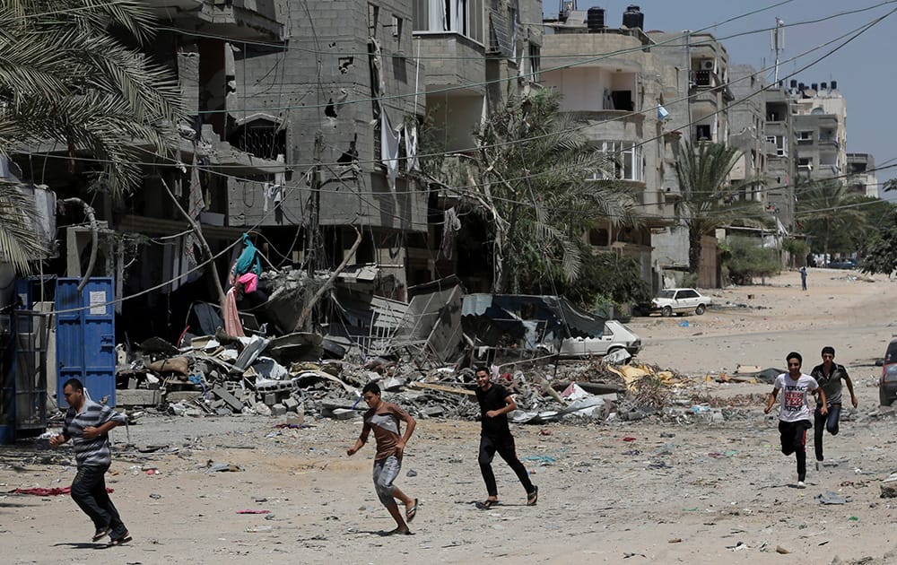 Palestinians run to take cover after an Israeli strike hits a three-story building belonging to the Abdul Hadi family in Gaza City in the northern Gaza Strip.