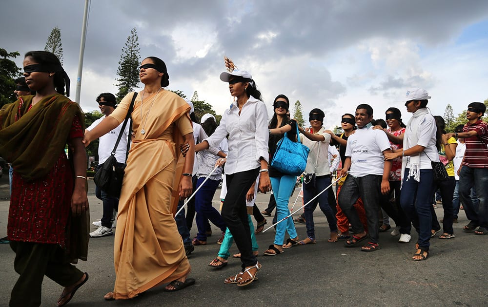 People with their eyes blindfolded join visually impaired people during a `Blind Walk` in Bangalore.