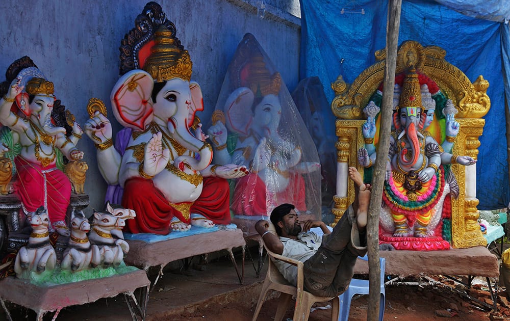 A vendor sits beside idols of elephant-headed Hindu god Ganesha as he awaits customers ahead of the Ganesh Chaturthi festival in Hyderabad.