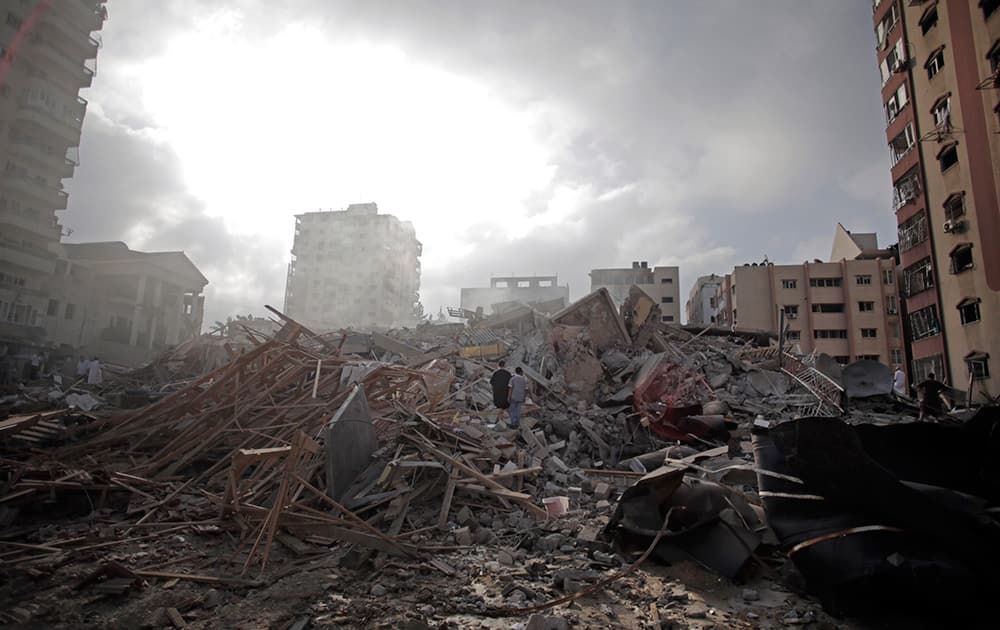 Palestinians inspect the rubble of the Al-Zafer apartment tower following Israeli airstrikes Saturday that collapsed the 12-story building, in Gaza City.