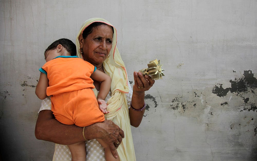 An Indian woman displays a mortar shell allegedly fired into a residential area from the Pakistan side at the India-Pakistan international border area of Ranbir Singh Pura, about 27 kilometers (17 miles) south of Jammu.