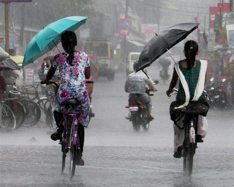 Girls use umbrellas while going to school in rains in Jalpaiguri.