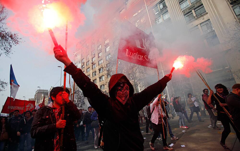 A protester holds a couple of flares during a student protest in Santiago, Chile.