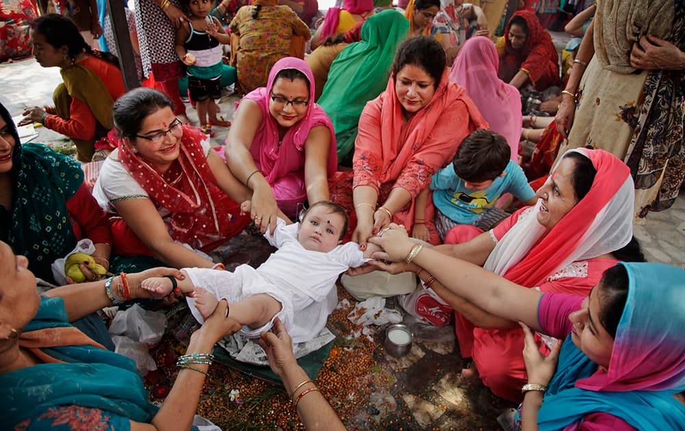 Hindu women belonging to the Dogra community swing a child as part of a ritual as they pray for the long life of their sons during the `Bacch Dua` festival in Jammu.