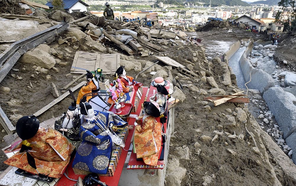 A set of Japanese hina dolls for the Girl`s Day celebration are placed on rubble as Japan Ground Self Defense Force personnel search for missing residents in a mud-ridden residential area following a massive landslide in Hiroshima, western Japan.