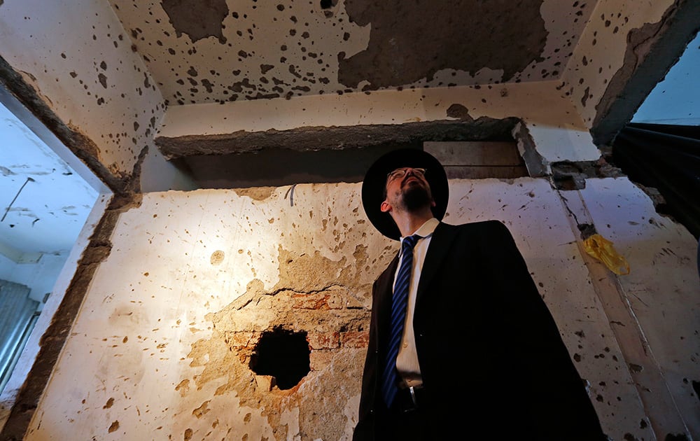 Rabbi Moshe Gourarie from New Jersey looks at a wall riddled with bullet marks from the 2008 terror attack at the Chabad Center, during the reopening of the Jewish center in Mumbai.