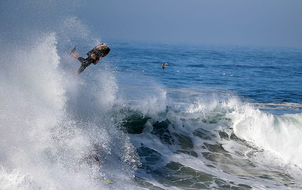 A bogieboarder flies over a wave a surfer rides underneatch a wave at the wedge in Newport Beach, Calif.